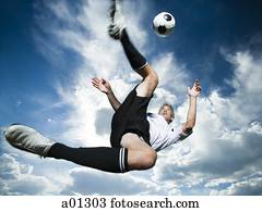 שחקן של כדורגל, בועט, כדור, בזמן, סילהאואטאד, נגד, a, מעונן, שמיים כחולים