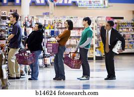 People waiting in line with shopping baskets at grocery store People waiting in line with shopping baskets at grocery store