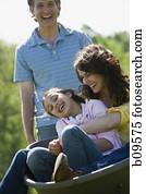 woman and her daughter sitting in a wheel barrow with a man standing beside them