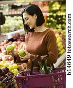 אישה מחזיקה, תפוחי עץ ירוקים, ב, מכולת, עם, סל של קניות