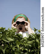 woman looking over a hedge with binoculars