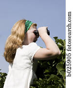 woman looking over a hedge with binoculars