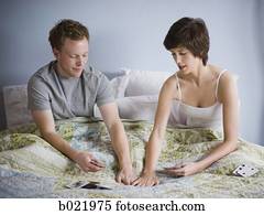 couple playing cards in bed