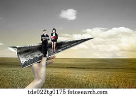 someone's hand holding paper airplane which has business people