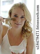 Blonde woman spreading on a healing earth mask