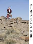 Man stands with mountain bike on rocky outcrop