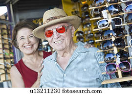 Portrait of senior couple trying on sunglasses, smiling