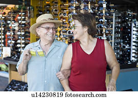 Senior couple trying on funny sunglasses, smiling