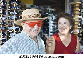 Senior couple trying on sunglasses, smiling