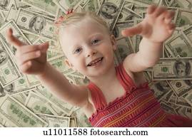 Young girl lying on a pile of money