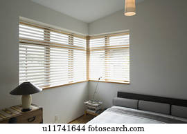Contemporary bedroom with gray bed and corner windows