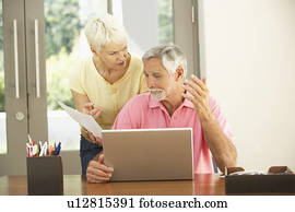 Worried Senior Couple Using Laptop At Home