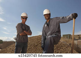 Portrait of two construction workers by rubble on building site