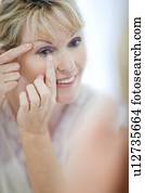 mulher sênior, pôr lentes contato