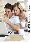 Young couple thinking and looking at a laptop computer
