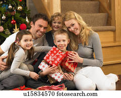 Family with gifts in front of Christmas tree