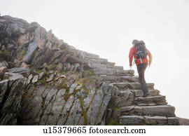 Hiker climbing rocky steps on hillside