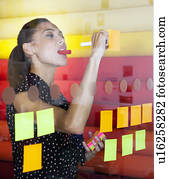 Businesswoman sticking notes on window