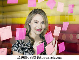 Businesswoman sticking notes on window