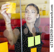 Businesswoman sticking notes on window