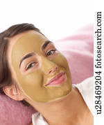 Young woman with healing earth face mask