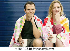 Couple relax with hot drinks on beach Couple relax with hot drinks on beach