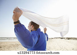 Sporty man celebrating at beach in sun