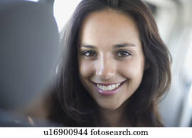 Young woman with dark hair in car smiling