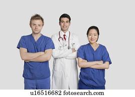 Portrait of diverse healthcare workers standing with hands folded over gray background