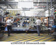 Workers with car body part in welding jig in car factory