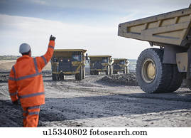 Worker directing trucks at surface mine