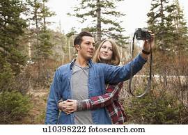 Young couple self photographing in non-urban scene