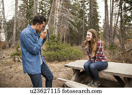 Young man photographing his girlfriend in non-urban scene