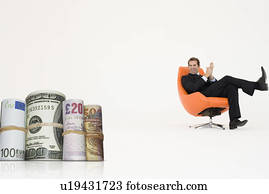 Happy businessman looking at money rolls representing growth in international business
