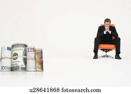Money rolls with pensive businessman on chair representing financial problems