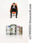 Money rolls with pensive businessman on chair representing financial problems