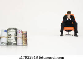 Money rolls with worried businessman on chair representing financial problems