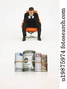 Money rolls with worried businessman on chair representing financial problems