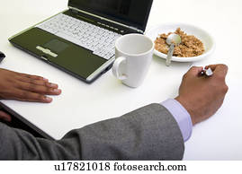 Close up of Indian mans hands writing on paper next to cereal