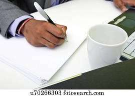 Close up of Indian mans hands writing on paper.