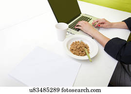 Close up of womans hands typing on laptop with mug in foreground
