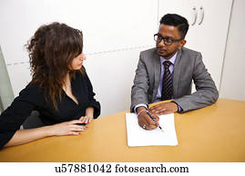 Multi-ethnic work colleagues signing paperwork on a table