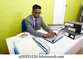 Portrait of Indian Businessman working on his laptop computer at his desk