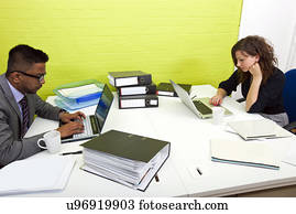 Side view of colleagues working at their desks opposite each other