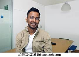 Young Indian man smiling at camera in his office 