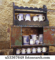 COLLECTIONS DISPLAYS - An antique open cupboard made by German immigrant in 1850. A collection of Salt Glaze Pottery on shelves, stone wall as background, Mineral Point Wis, Jail House Antiques 