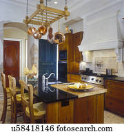 KITCHENS - Upscale country/traditional look, overall of island and stove. Custom wood cabinets with warm stain. Copper pots hang from rack. Bar stools, straight edge granite counters, inset wood cutting board, molding, range hood with plaster corbels, and KITCHENS - Upscale country/traditional look, overall of island and stove. Custom wood cabinets with warm stain. Copper pots hang from rack. Bar stools, straight edge granite counters, inset wood cutting board, molding, range hood with plaster corbels, and