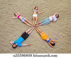 Aerial view of friends lying in star shape on sand