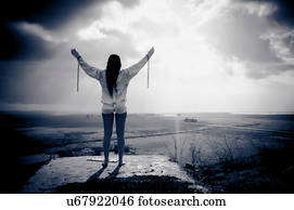 Woman wearing chains and straitjacket looking out over land