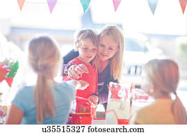 Two young sisters selling drink to brother and mother